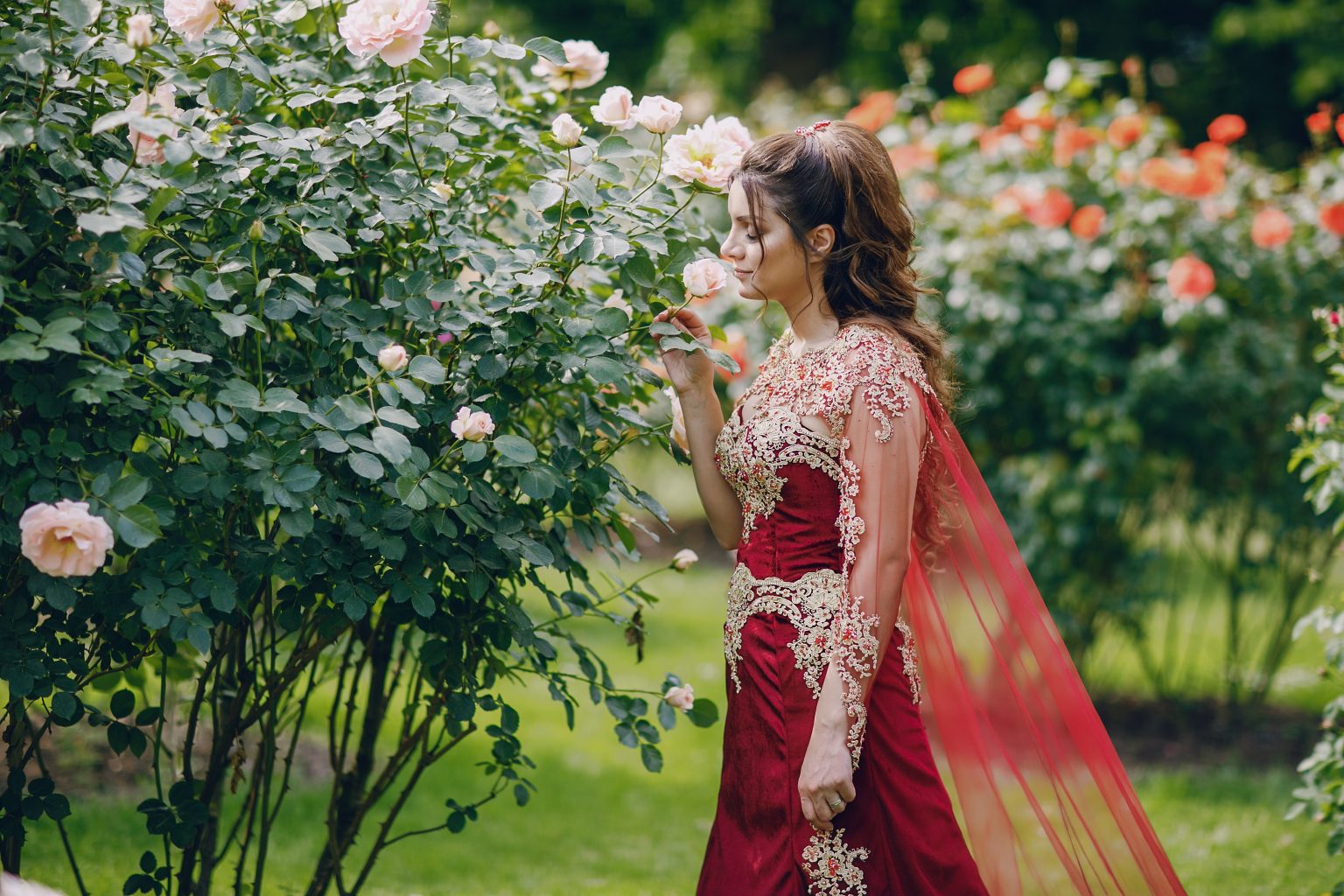 A beautiful Turkish girl in a long red dress walks in the summer old city